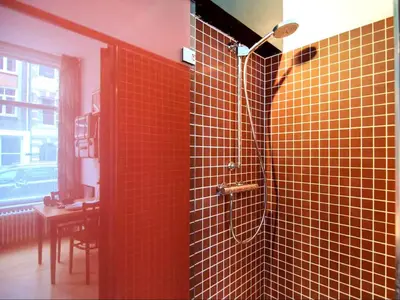 a bathroom with a shower with orange tiled walls at AibarResidentieJH in Amsterdam