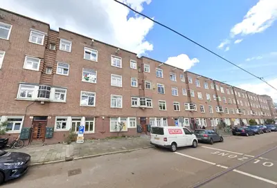 a large brick building with a white van parked in a parking lot at AibarResidentieJH in Amsterdam