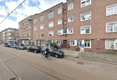 a woman riding a bike down a street in front of a building at AibarResidentieJH in Amsterdam