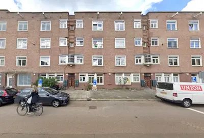 a woman riding a bike in front of a building at AibarResidentieJH in Amsterdam
