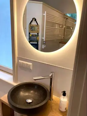 a bathroom with a sink with a round mirror at OscarReestratResidence in Amsterdam