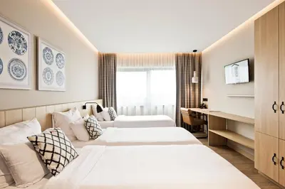 a hotel room with two beds and a desk at Urban Lodge Hotel in Amsterdam