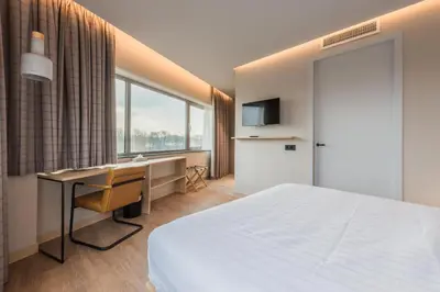 a bedroom with a bed and a desk and a window at Urban Lodge Hotel in Amsterdam
