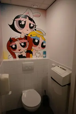 a bathroom with a painting on the wall next to a toilet at Dutchies Hostel in Amsterdam