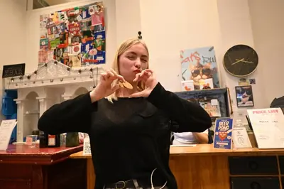 a woman eating a piece of food in a store at Dutchies Hostel in Amsterdam