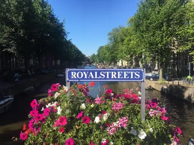 a blue street sign in front of flowers at Amsterdam Barangay in Amsterdam
