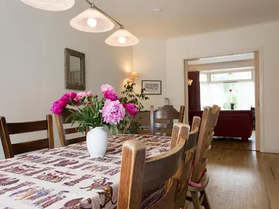 a dining room table with a vase of flowers on it at Egmond-vakantiewoningen in Egmond aan Zee