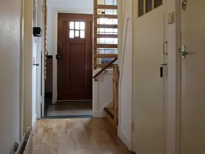 a hallway with a wooden door and a stair case at Egmond-vakantiewoningen in Egmond aan Zee