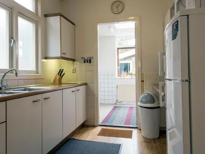 a kitchen with a sink and a door to a bathroom at Egmond-vakantiewoningen in Egmond aan Zee