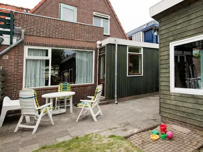 a patio with two chairs and a table and a table at Egmond-vakantiewoningen in Egmond aan Zee