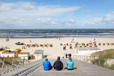 a group of people sitting on a pier looking at the beach at Egmond-vakantiewoningen in Egmond aan Zee