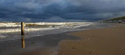 a beach with a stormy sky and the ocean at Egmond-vakantiewoningen in Egmond aan Zee