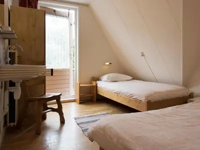 a attic room with two beds and a window at Egmond-vakantiewoningen in Egmond aan Zee