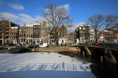 a river in a city with buildings and a bridge at Canal Studio Apartment in Amsterdam