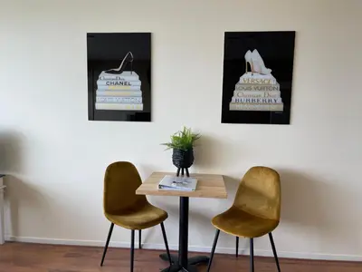 a table and two chairs in a room with three paintings at Studio Coastview in Zandvoort