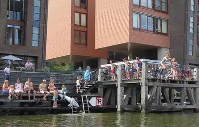 a group of people sitting on a dock near the water at Houseboat Westerdok in Amsterdam