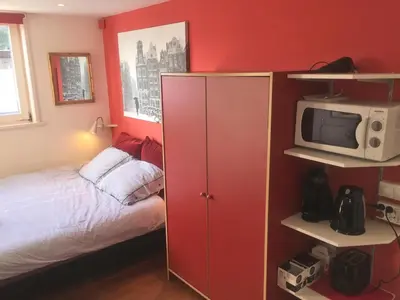 a small bedroom with a bed and a red wall at Houseboat Westerdok in Amsterdam