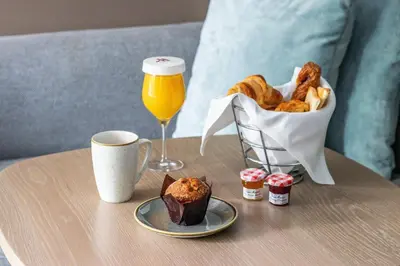 a table with a glass of orange juice and a basket of pastries at Amsterdam Marriott Hotel in Amsterdam