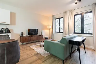 a living room with a green couch and a tv at UtrechtCityApartments – Weerdsingel in Utrecht