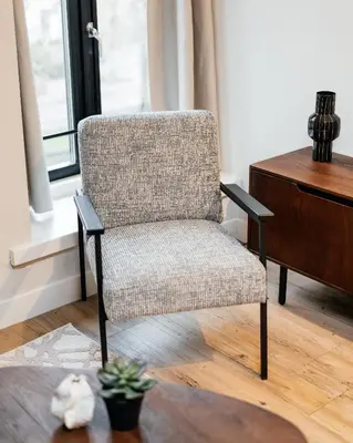 a chair sitting in a living room next to a desk at UtrechtCityApartments – Weerdsingel in Utrecht