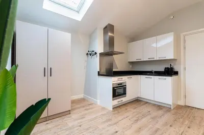 a kitchen with white cabinets and a skylight at UtrechtCityApartments – Weerdsingel in Utrecht