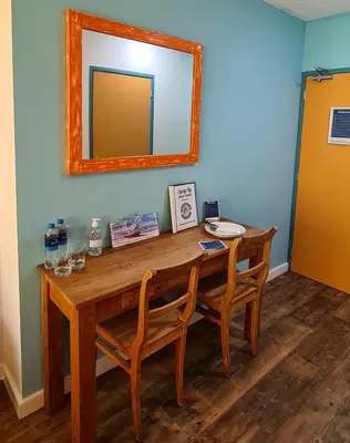 a wooden table with two chairs and a mirror at The Flying Pig Beach Hostel Age 18 to 40 in Noordwijk aan Zee