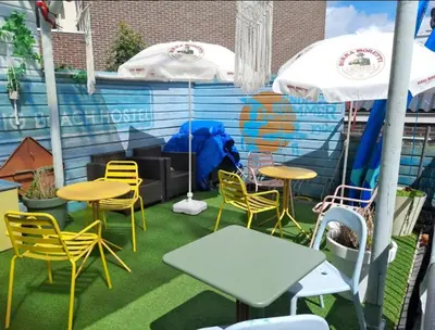 a patio with tables and chairs and umbrellas at The Flying Pig Beach Hostel Age 18 to 40 in Noordwijk aan Zee