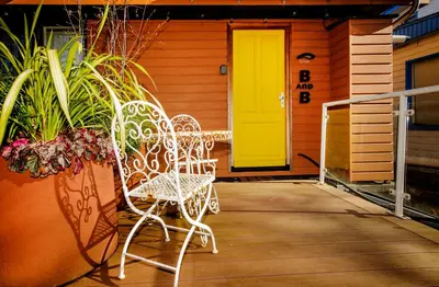 a pair of chairs sitting on a porch with a yellow door at Houseboat studio with canalview and free bikes in Amsterdam
