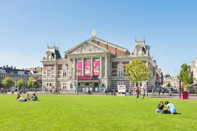 people sitting on the grass in front of a building at Houseboat studio with canalview and free bikes in Amsterdam