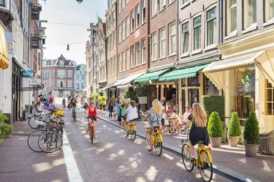 a group of people riding bikes down a street at Houseboat studio with canalview and free bikes in Amsterdam
