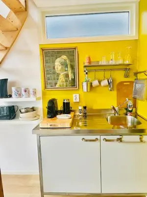 a kitchen with a sink and a yellow wall at Houseboat studio with canalview and free bikes in Amsterdam