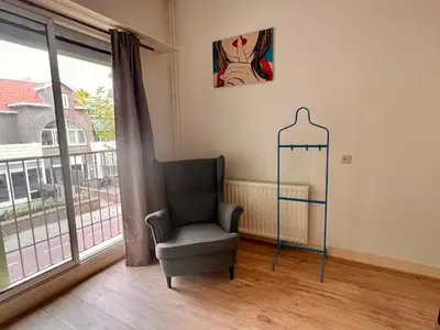 a living room with a chair and a window at Zandvoort Station Apartment in Zandvoort