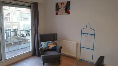 a living room with a chair and a window at Zandvoort Station Apartment in Zandvoort