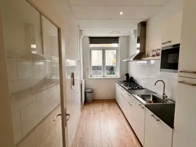 a kitchen with white cabinets and a sink and a window at Zandvoort Station Apartment in Zandvoort