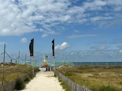 a path leading to a building on a beach with flags at Holiday Home Plevier Comfort-1 by Interhome in Noordwijk