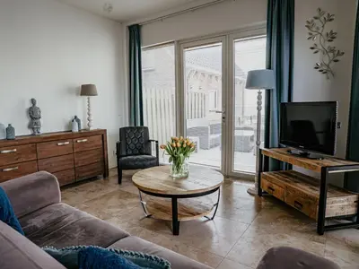a living room with a couch and a tv and a table at Holiday Home De Zeeparel by Interhome in Egmond aan Zee