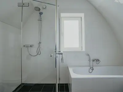 a white bathroom with a shower and a bath tub at Holiday Home De Zeeparel by Interhome in Egmond aan Zee