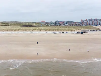 a group of people walking on the beach at Holiday Home De Zeeparel by Interhome in Egmond aan Zee