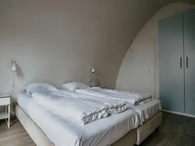 a large white bed in a room with a white wall at Holiday Home De Zeeparel by Interhome in Egmond aan Zee