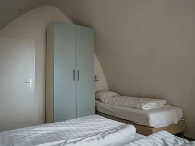 a bedroom with two beds and a cabinet at Holiday Home De Zeeparel by Interhome in Egmond aan Zee