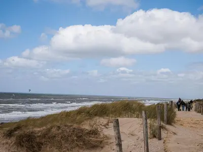 a beach with people riding horses on the sand at Holiday Home De Zeeparel by Interhome in Egmond aan Zee
