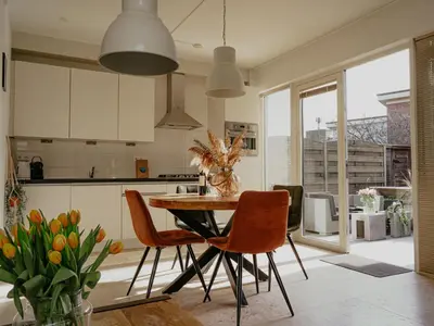 a kitchen with a table and chairs and a kitchen with white cabinets at Holiday Home De Zeeparel by Interhome in Egmond aan Zee