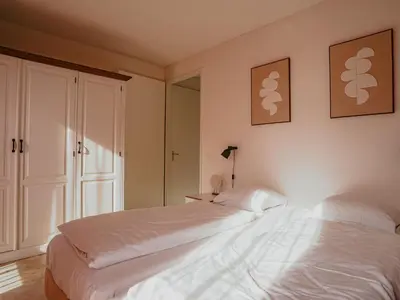 a bedroom with a large white bed and a mirror at Apartment De Zeeparel by Interhome in Egmond aan Zee