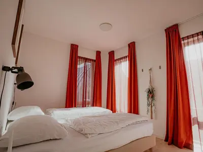 a bedroom with two beds and red curtains at Apartment De Zeeparel by Interhome in Egmond aan Zee