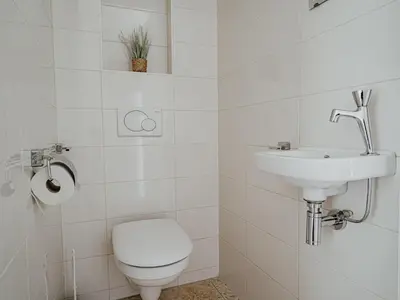 a white bathroom with a toilet and a sink at Apartment De Zeeparel by Interhome in Egmond aan Zee
