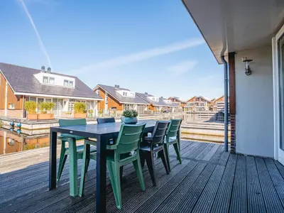 a table and chairs on a deck with a view of houses at Holiday Home Busch en Dam by Interhome in Uitgeest