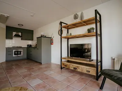 a living room with a fireplace and a kitchen at Holiday Home Busch en Dam by Interhome in Uitgeest
