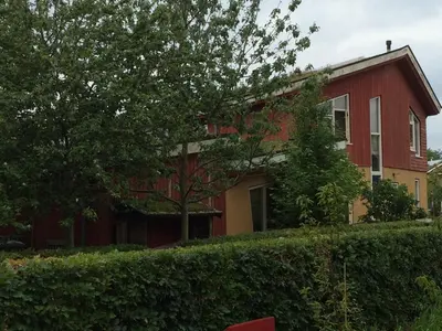 a red house with a tree in front of it at B&B 't Buitenkansje in Almere