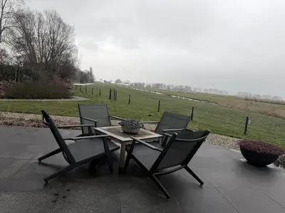 a patio with a table and chairs and a field at Aan de Amstel in De Hoef