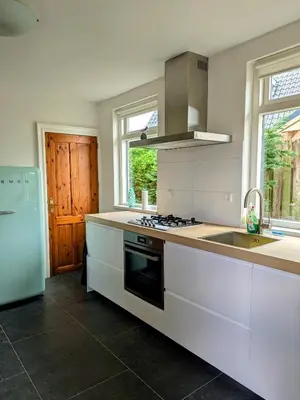 a white kitchen with a sink and a refrigerator at Le-Clochard in Groet